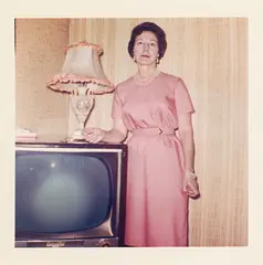 A woman standing beside a television set