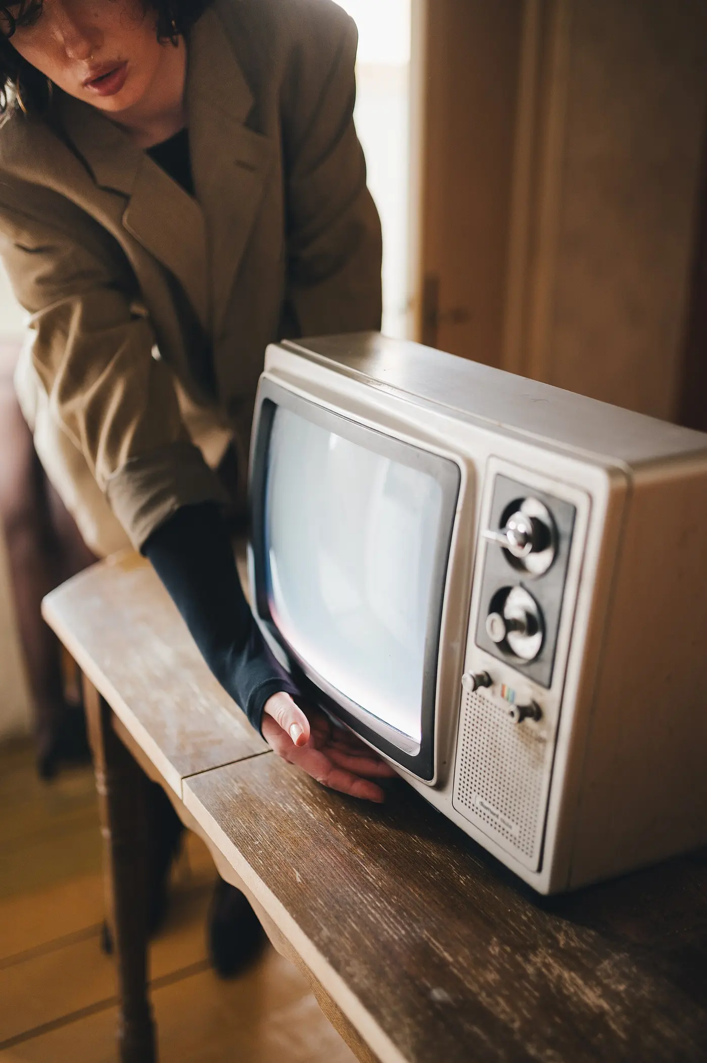 A woman adjusting a vintage television set. Third attempt: the first was a photograph of Saturn captioned as 'a screen, and the person watching it', the second a film-festival award badge. Both passed the must-term test. The caption had been written before the picture was chosen, which is the failure this review exists to catch.